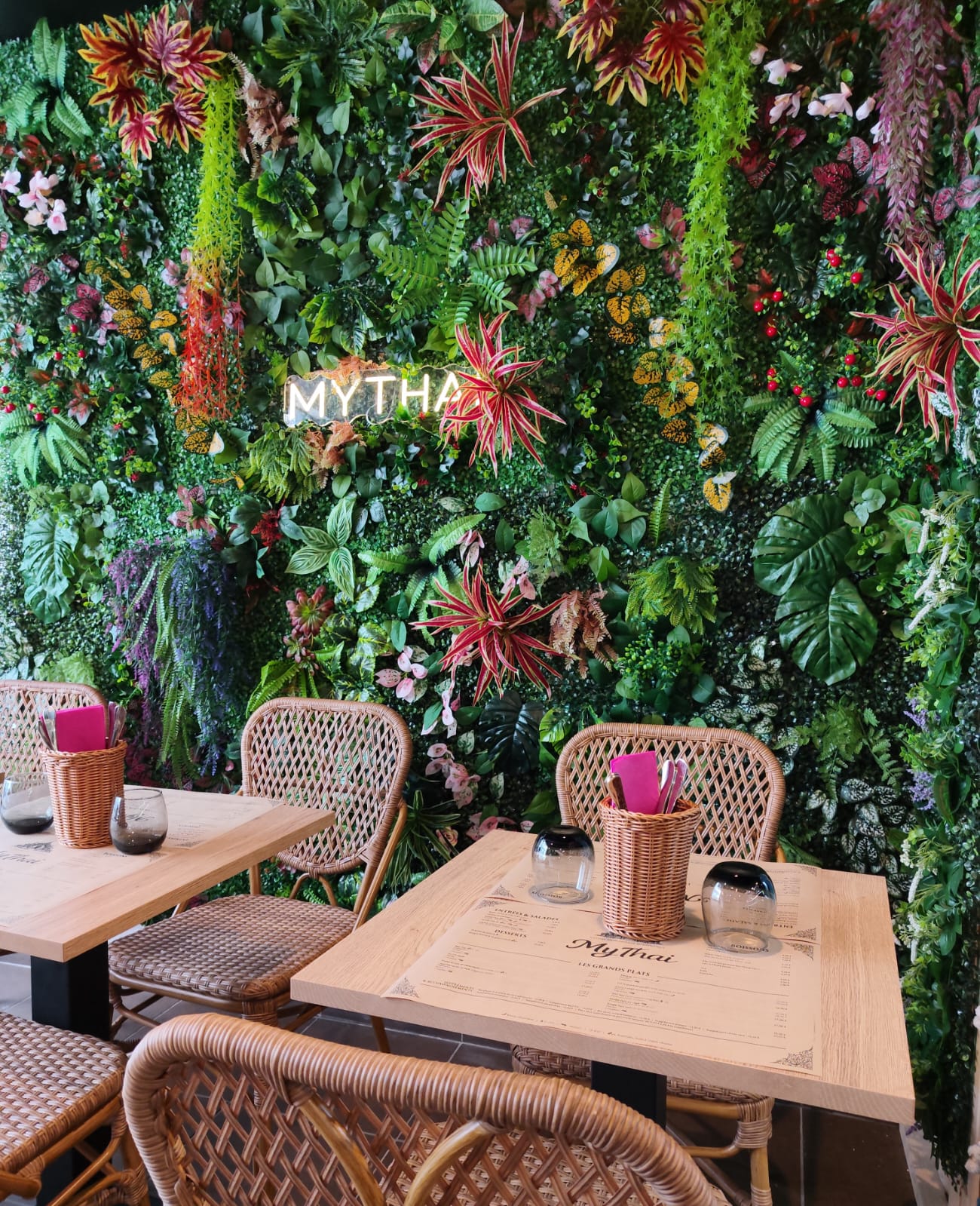 Salle du restaurant MYTHAI à Évian-les-Bains, mur végétal et enseigne lumineuse